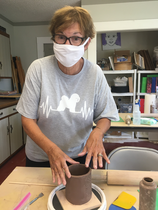 A woman is working with clay in a pottery studio.