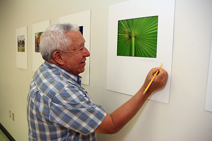 A man signs his photograph which is part of an exhibition.